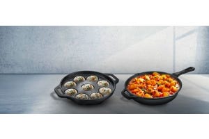 Cast iron cookware set featuring an appam pan with cooked appams and a skillet filled with curry, placed on a kitchen countertop