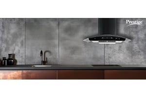Prestige black kitchen chimney installed in a modern kitchen with dark grey walls and brown cabinets, enhancing ventilation and smoke-free cooking.