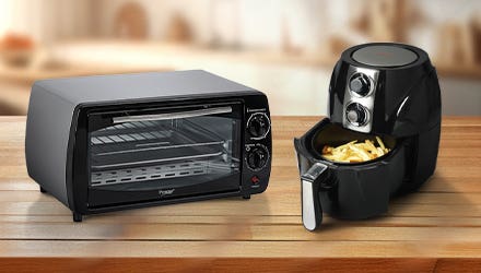 A black convection oven and a black air fryer with fries inside, placed on a wooden countertop