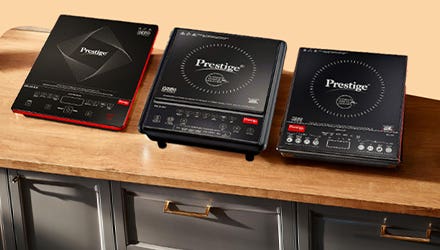 Three Prestige induction cooktops placed on a wooden countertop