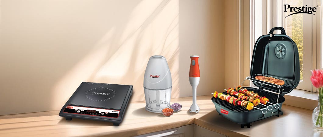 Prestige kitchen appliances including a black induction cooktop, chopper, orange hand blender, and portable charcoal grill 