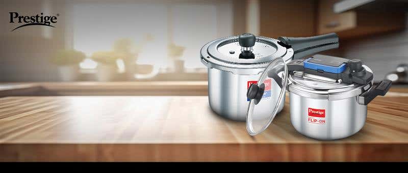 Prestige stainless steel pressure cookers displayed on a kitchen countertop, featuring the Flip-On model and classic design