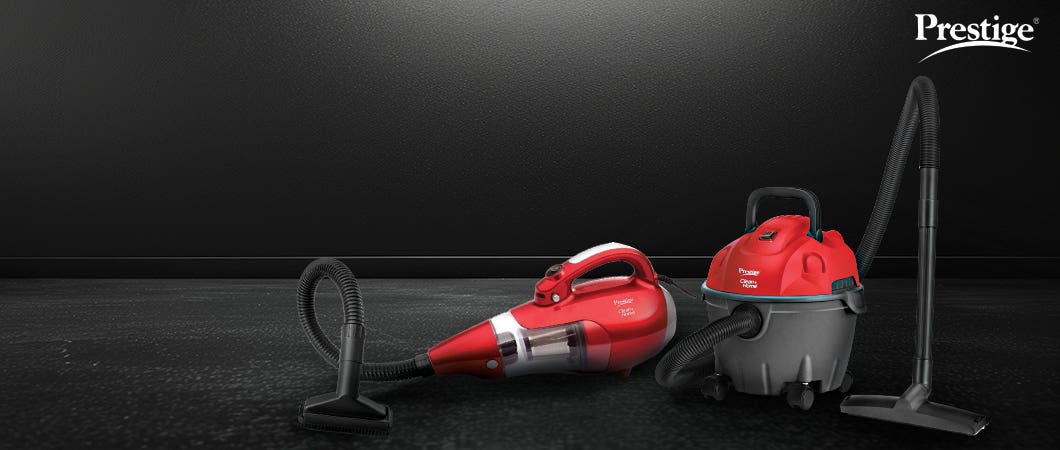 Two red Prestige vacuum cleaners, including a handheld and a wet-dry model, placed on a black surface for efficient home cleaning.